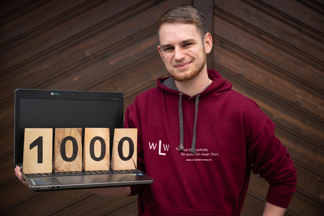Tobias Schär hält einen Laptop fest. Darauf stehen die Zahl 1000. Jede Zahl ist ein einzelner Holzblock.