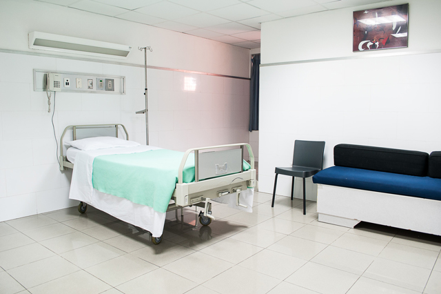 In einem Spitalzimmer steht ein leeres Bett. Das Bett ist frischbezogen und bereit für einen Patienten oder eine Patientin.