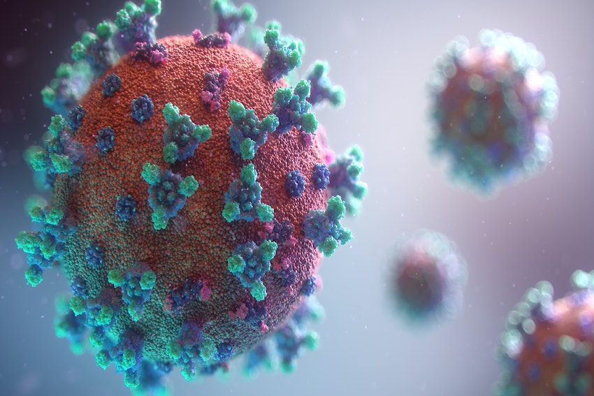 In der linken Bildhälfte schwebt ein Corona-Virus. Im Hintergrund sind in der rechten Bildhälfte zwei weitere, kleinere Corona-Viren zu sehen.