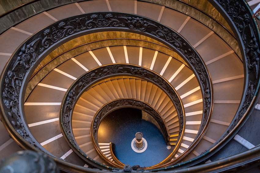 Eine grosse Wendeltreppe mit reich verziertem Geländer in einem Gebäude im Vatikan in Rom.