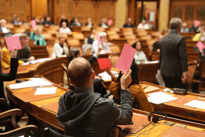 Parlamentarierinnen und Parlamentarier stimmen mit einem rosa Zettel ab.