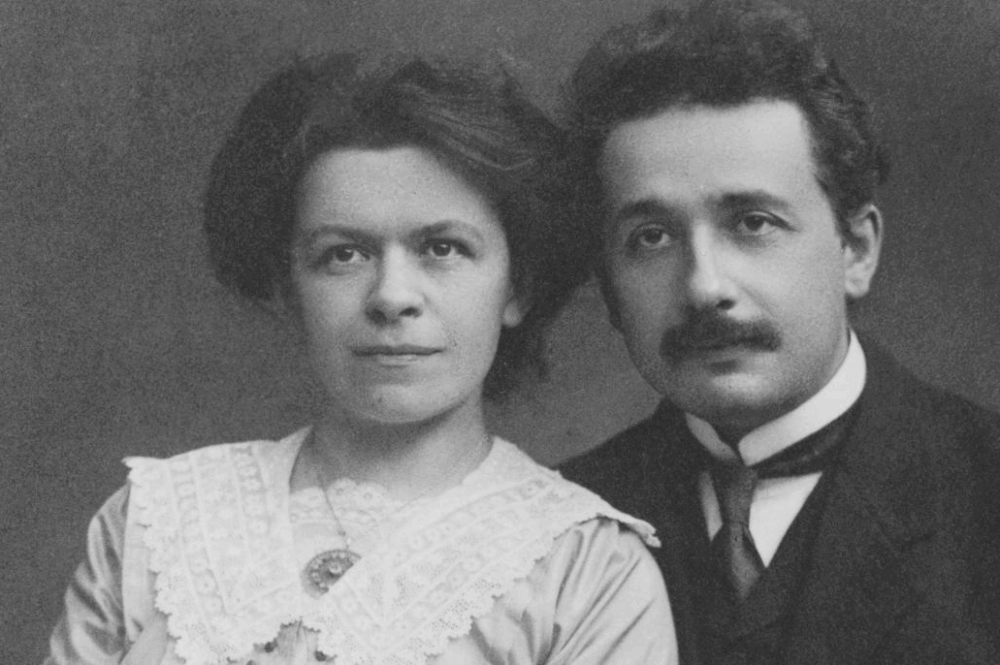 Auf dem Foto sind Mileva Marić und Albert Einstein. Das Foto ist schwarz-weiss. Beide sind elegant angezogen, Mileva trägt eine Spitzenbluse und Albert einen Anzug.