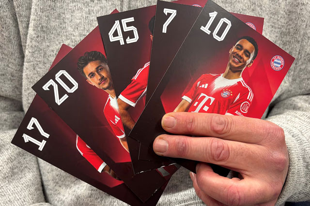 Eine Hand h&auml;lt einen F&auml;cher aus f&uuml;nf hochformatigen Sammelkarten mit dunklem Hintergrund. Jede Karte zeigt eine R&uuml;ckennummer (17, 20, 45, 7, 10) sowie ein Portr&auml;tfoto einer Person im FC-Bayern-Trikot.