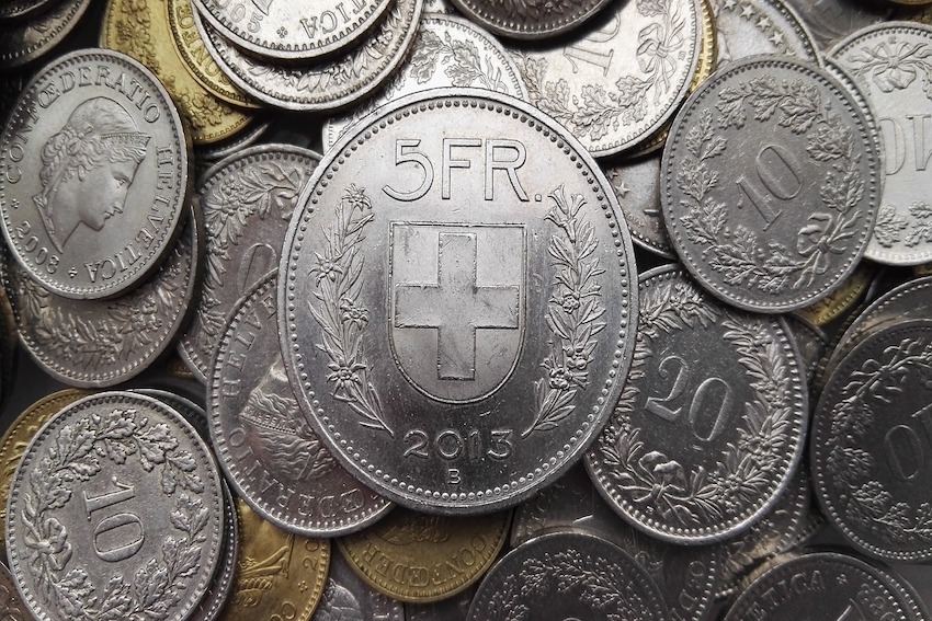 Viele Schweizer Geldmünzen, in der Mitte ein Fünffränkler.